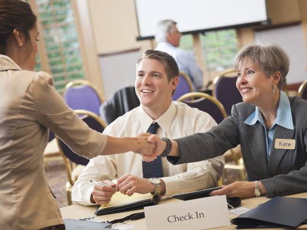 two businesswomen shake hands at a job fair